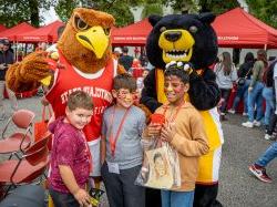 A red hawk and a bear mascot pose with three children with painted faces.