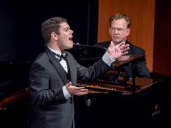 Male student singing at recital with pianist accompaniment